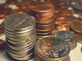 A photo of coins; separate stacks of nickels, pennies, quarters, and dimes