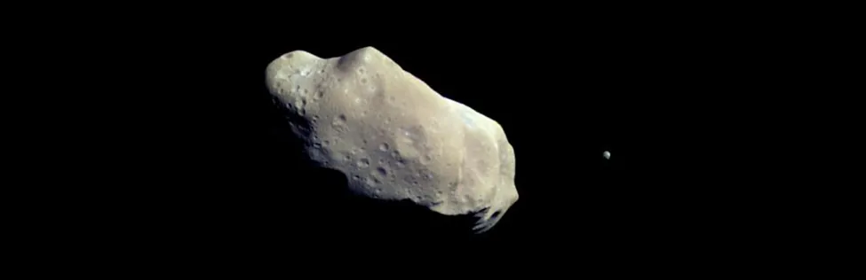 Ida and Dactyl. In this image the moon Dactyl is seen to the right of the elongated, cratered asteroid Ida.