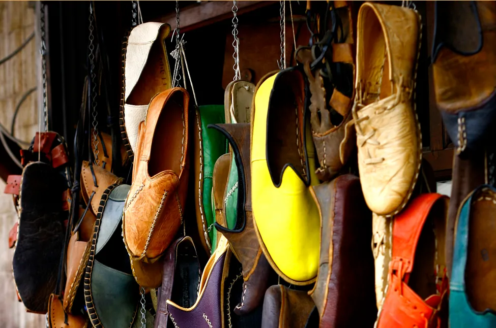 Esta foto muestra muchos pares de zapatos diferentes de varios colores. Los zapatos parecen estar colgados de una pared por los cordones.