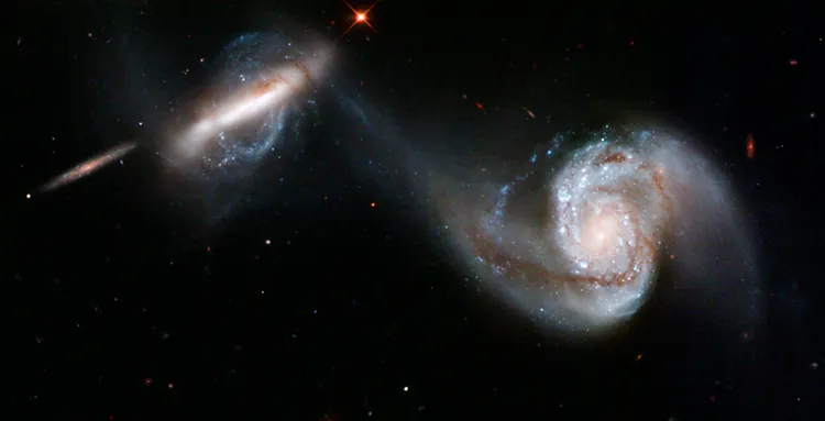Two spiral galaxies show the strong gravitational attraction between them as their arms appear to reach out toward one another.