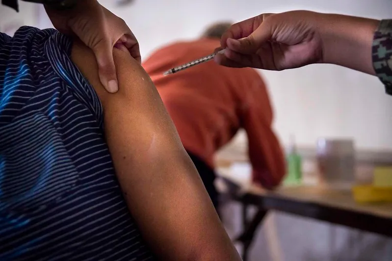 Photo shows a person receiving an injection in the arm.