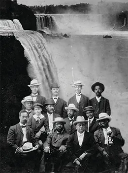 A photograph shows ten posed men, one of whom sits with a little boy. W. E. B. Du Bois is seated in the center.