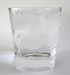 A photo of a glass of ice water filled to the brim.