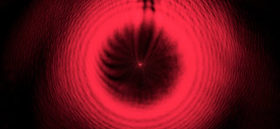 Zdjęcie pokazuje serię czerwonych, koncentrycznych kręgów na czarnym tle. W środku lśni czerwona plamka.