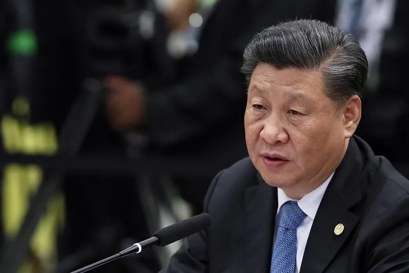 Chinese President Xi Jinping sits in front of a microphone.