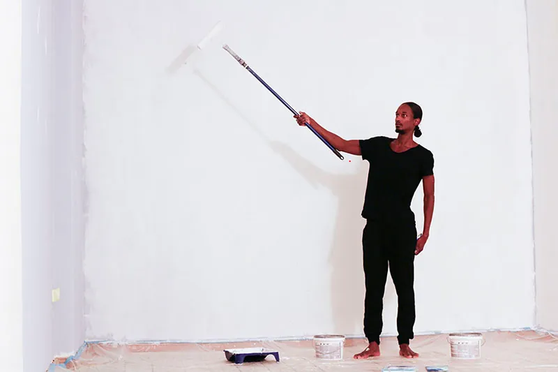 A person painting a wall using a paint roller.