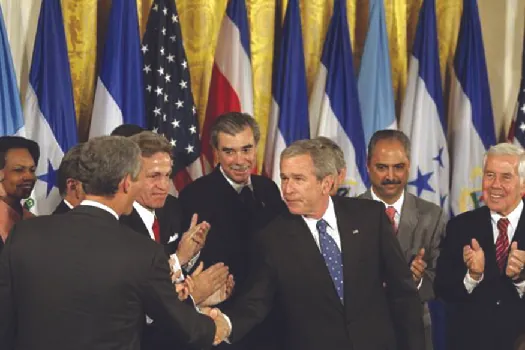 An image of George W. Bush shaking hands with legislators and administration officials.