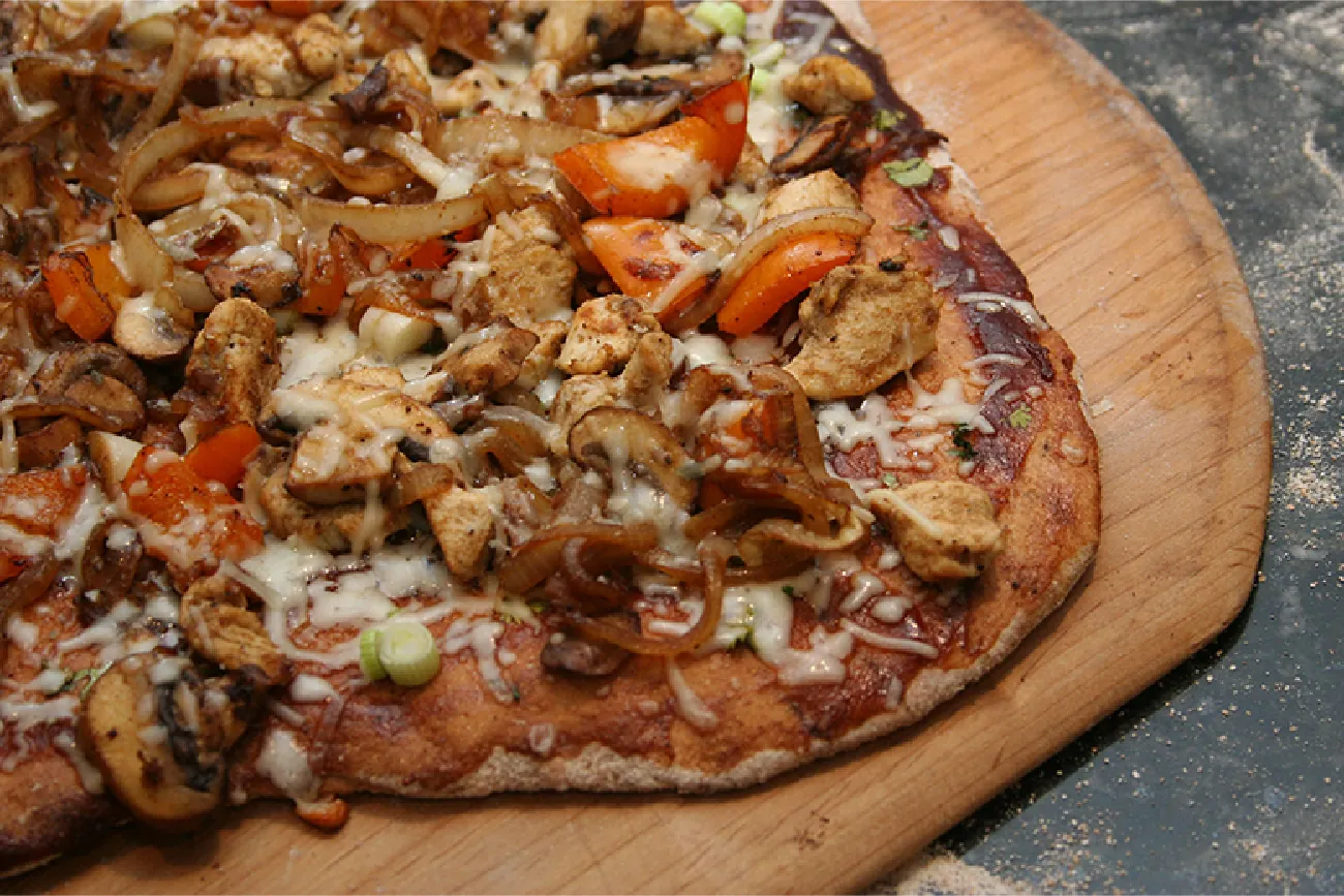 Image of a pizza peel with mushroom and arugula.