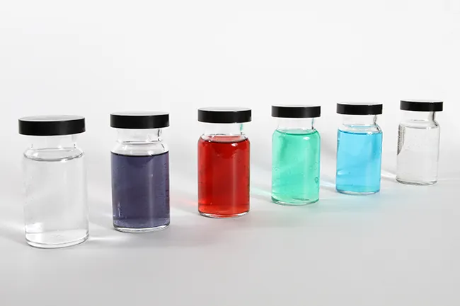 This figure shows six containers. Each is filled with a different color liquid. The first appears to be clear; the second appears to be purple; the third appears to be red; the fourth appears to be teal; the fifth appears to be blue; and the sixth also appears to be clear.