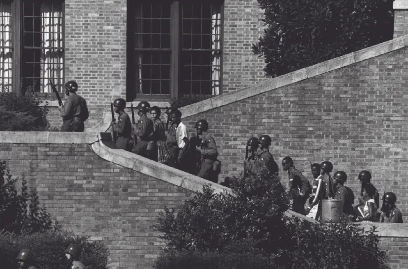 An image of armed people in helmets, escorting several children up a brick stairway.