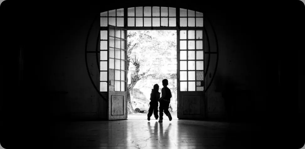 A photograph shows two children running outside through an open doorway.