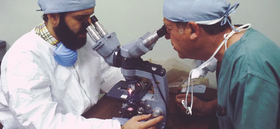 A photo of two scientists operating a microscope.