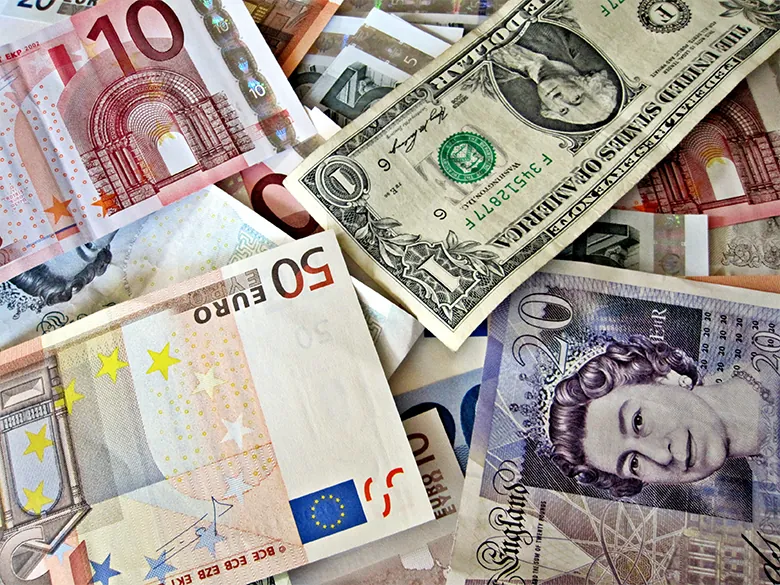 A photograph shows many different currencies from around the world, including the U.S. (dollars), UK (pounds), and Europe (euros).