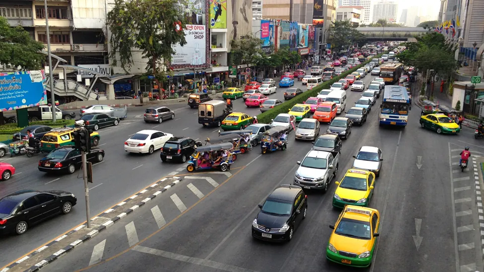 Esta es una imagen de una calle de la ciudad con una señal de tráfico. La imagen tiene carriles muy transitados de tráfico en ambas direcciones.