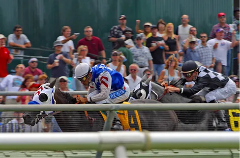 Picture shows two racehorses with riders accelerating out of the gate.