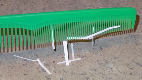 A photograph of thin strips of paper stuck to a plastic comb.