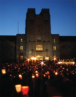 A photograph shows a massive crowd gathered in darkness in front of a large university building, holding candles.