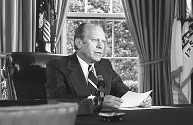 A photograph shows Gerald Ford seated at a desk with a sheet of paper before him, speaking into a microphone.