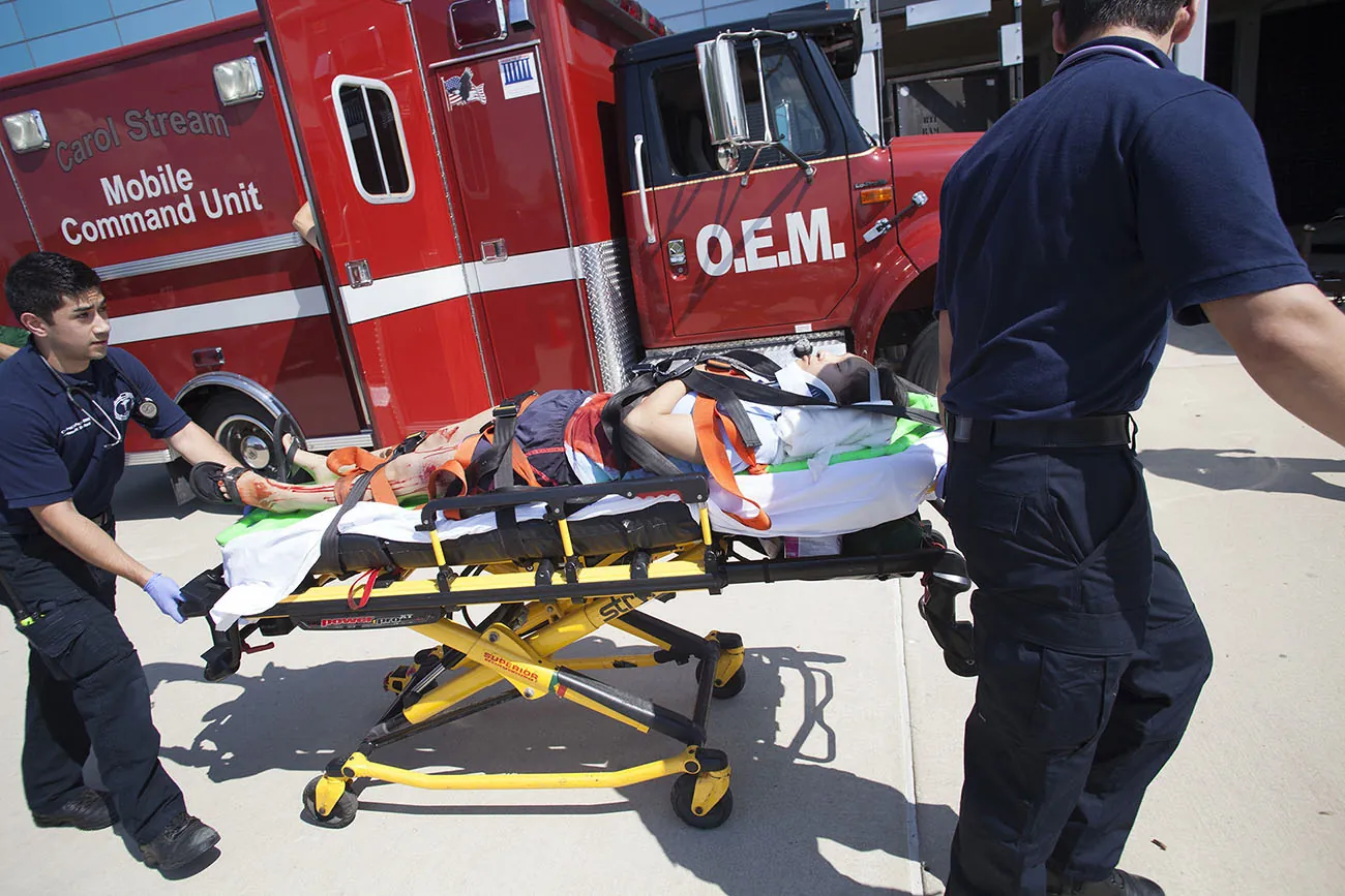 Emergency medical workers push a gurney with a patient.