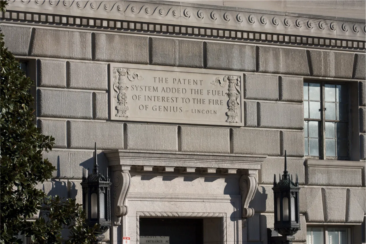 An image of the quote above the entrance to the Department of Commerce building in Washington, DC. It reads, THE PATENT SYSTEM ADDED THE FUEL OF INTEREST TO THE FIRE OF GENIUS - LINCOLN