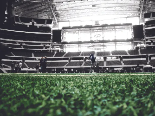 A photo of the inside of a football stadium, showing the field in the foreground and rows of empty seats in the background.