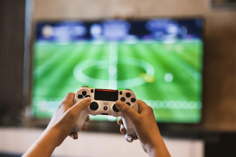A photo shows hands operating a game controller and playing football on the Playstation.