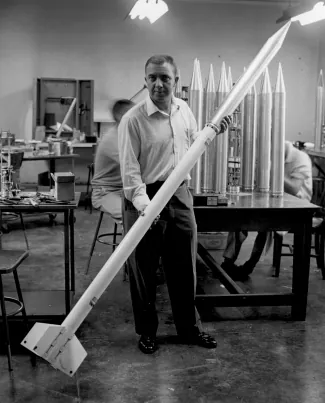 Photograph of James Van Allen holding a small rocket, which was part of a “rockoon”.