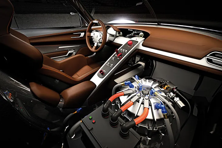 Figura jest fotografią urządzenia do odzyskiwania energii kinetycznej w samochodzie, zainstalowanego obok siedzenia kierowcy.