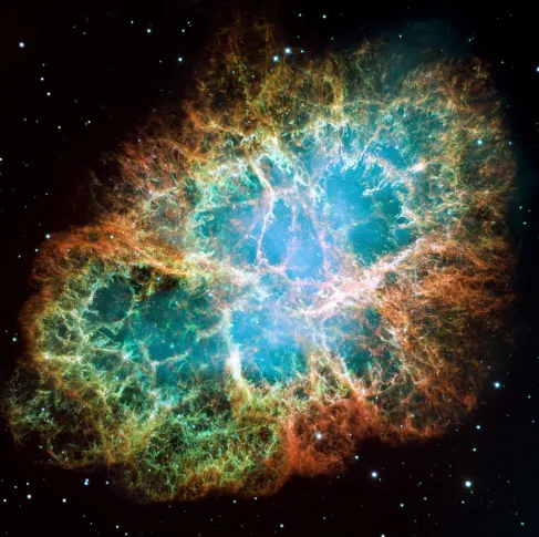 Image of the Crab Nebula Supernova Remnant. An oblong region of diffuse light, with delicate wisps and tendrils of gas, are seen expanding outward into the blackness of space.