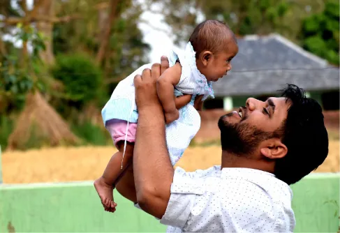A man holds a baby in the air.