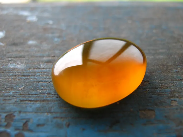 This piece of gold-colored amber from Malaysia has been rubbed and polished to a smooth, rounded shape.
