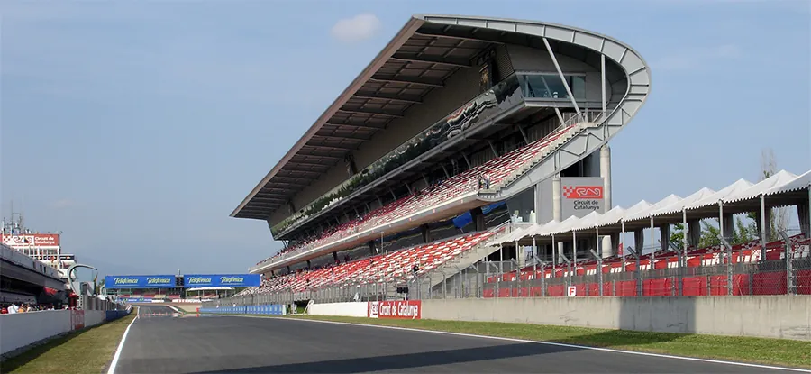 A photo of a grandstand next to a straightaway of a race track.