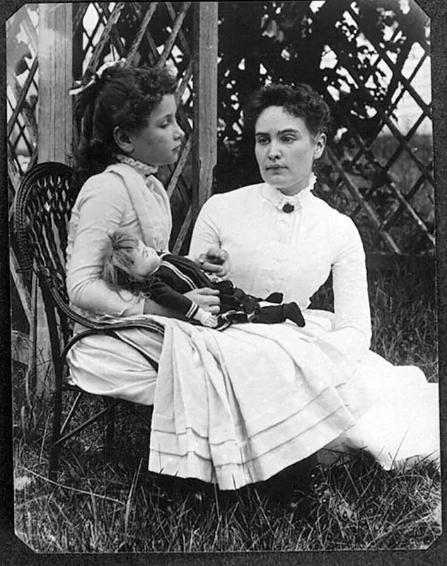 Helen Keller, a child, sits with Anne Sullivan, her adult teacher, in July of 1888.
