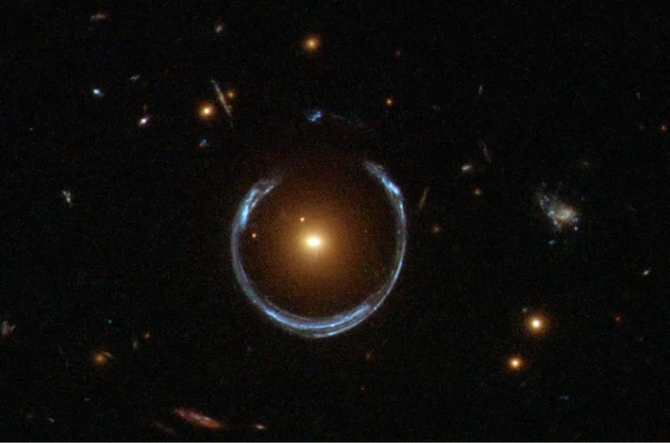 Zdjęcie czarnego nieba. Na środku mamy źródło żółtego światła, a wokół niego pierścień światła koloru białego.