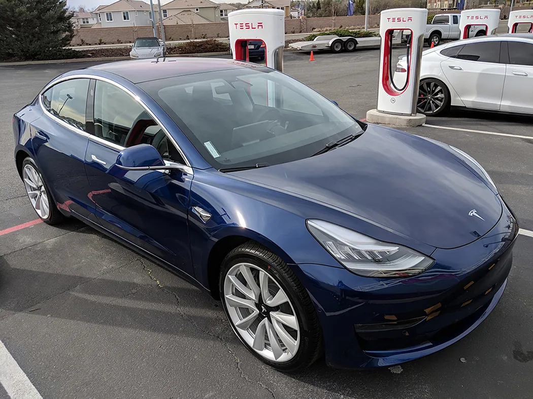 A photo shows a Tesla Model 3 electric car pictured at one of its supercharger stations.