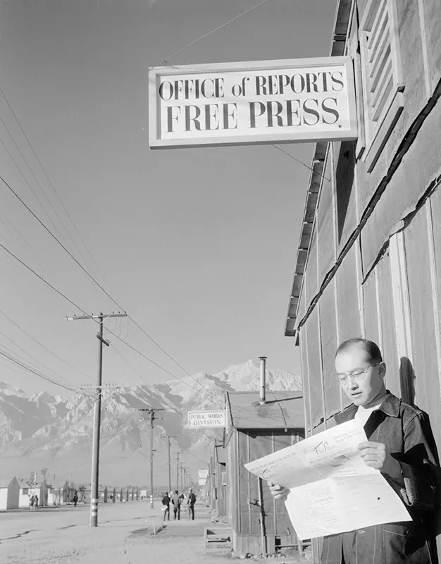 Roy Takeno, editor of the Manzanar Free Press, reads the newspaper at the internment camp in Manzanar, California, 1943.