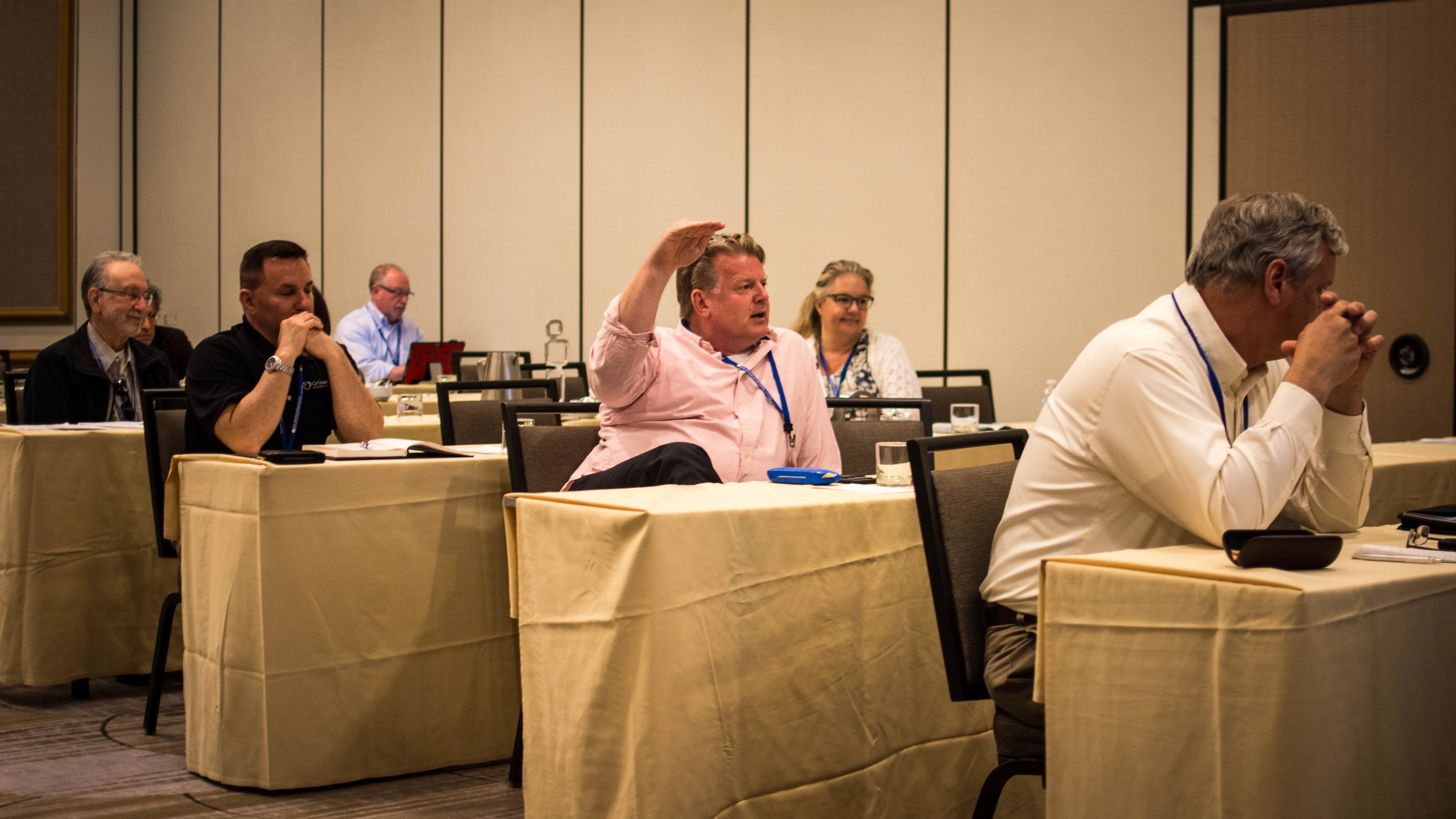 A photo shows Brian Schnell raising his hand vehemently while speaking to other franchisee attorneys during a meeting.