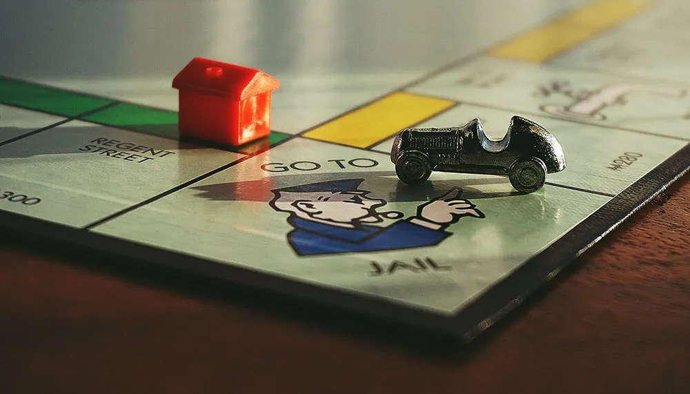 A photo shows the board game Monopoly in which the car game piece has landed on the GO TO JAIL space.