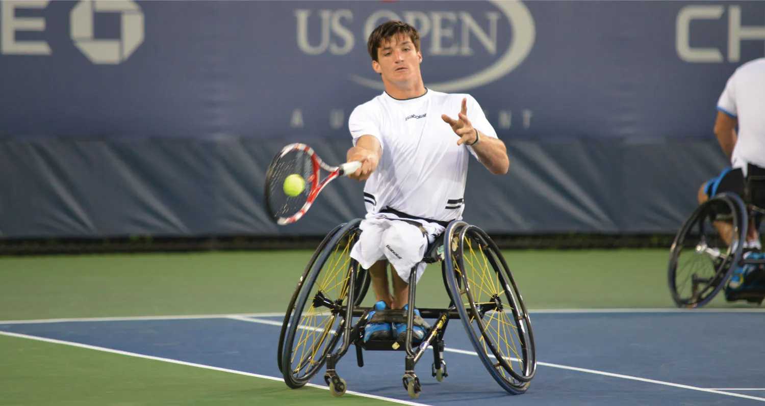 A tennis player in a wheelchair on a tennis court strikes a ball as it meets their racket.