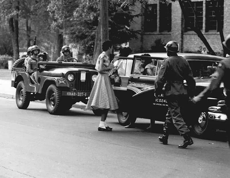 A black-and-white photo shows African-American students arrive at Central High School in Little Rock in army vehicles, escorted by soldiers from the 101 Airborne Division.
