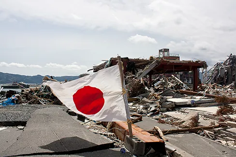 Photo of the aftermath of the earthquake in Japan with a focus on the Japanese flag.