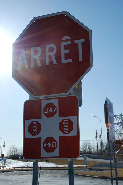 A photo shows the close-up of a French stop sign that reads “Arret.”