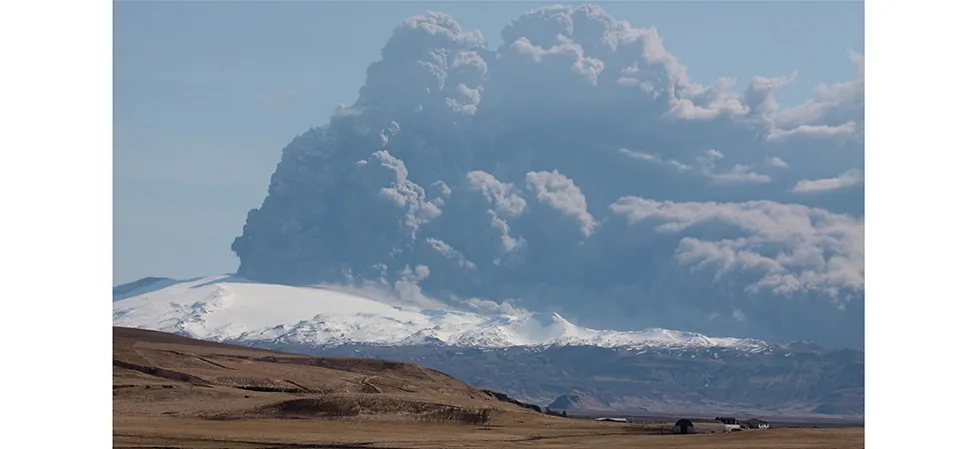 Una fotografía de un volcán en erupción. Se puede ver un gigantesco penacho de gas y polvo que se expulsa de él.