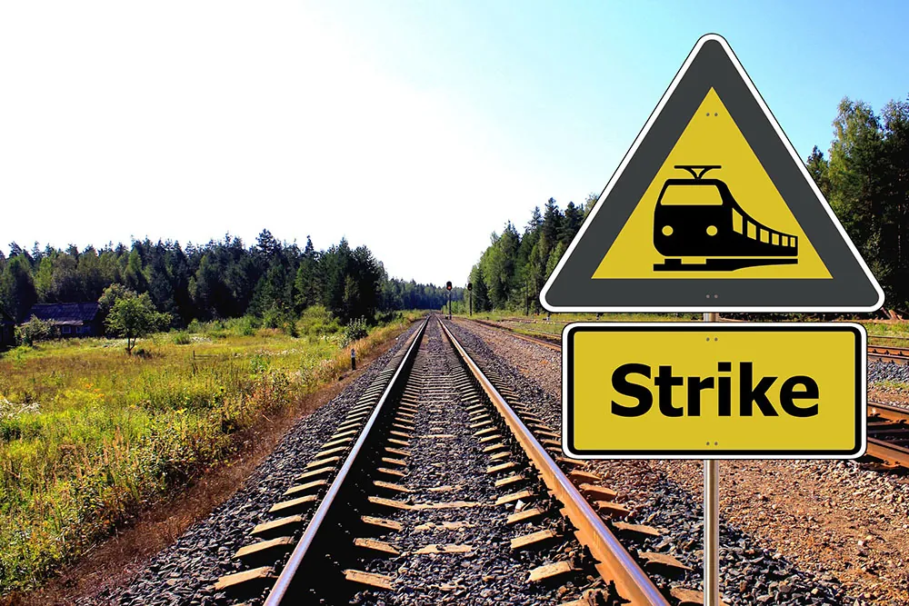 An image of an empty railroad track, accompanied by a sign that contains the word “strike.”