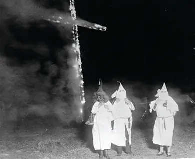 A photograph shows several hooded Klan members standing in front of a burning cross.