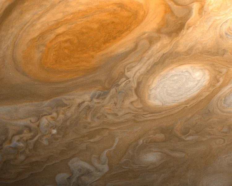 The picture shows what looks like a flowing orangish liquid into which some milk has been mixed. The main features are two eddies or vortices: a larger one that is a darker orange than the background and the other, smaller one, that is more milky than the background.