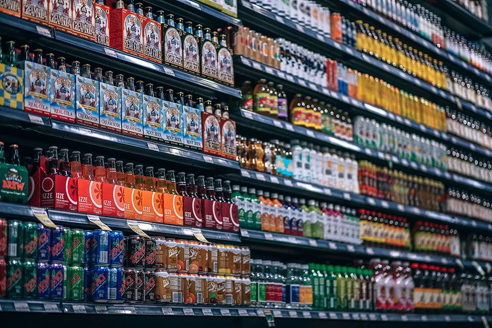 A photo shows store shelves with different bottles and cans of soft drinks.