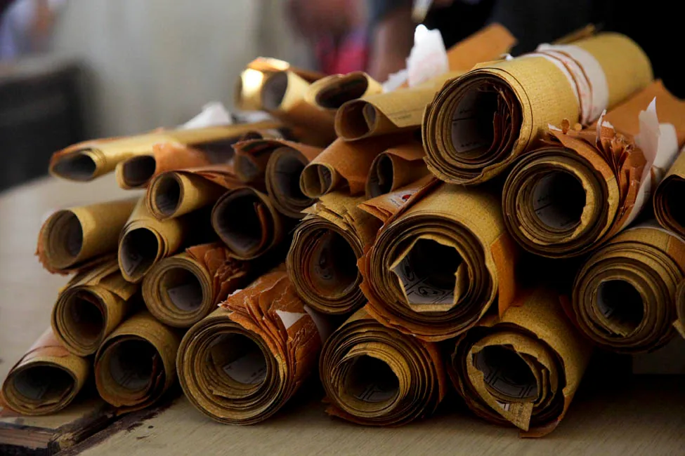 La foto muestra cerca de 26 rollos de papel apilados. Los rollos son de diferentes tamaños.