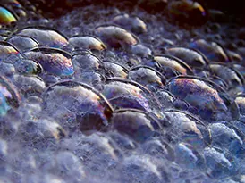 The figure is a picture of soap bubbles showing red, blue, green, violet, and yellow light reflecting from various bubbles.
