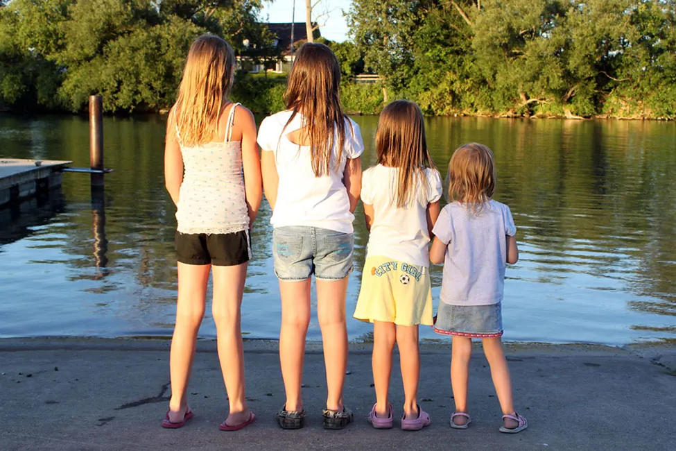 A group of four people are standing in a line in order by increasing height.